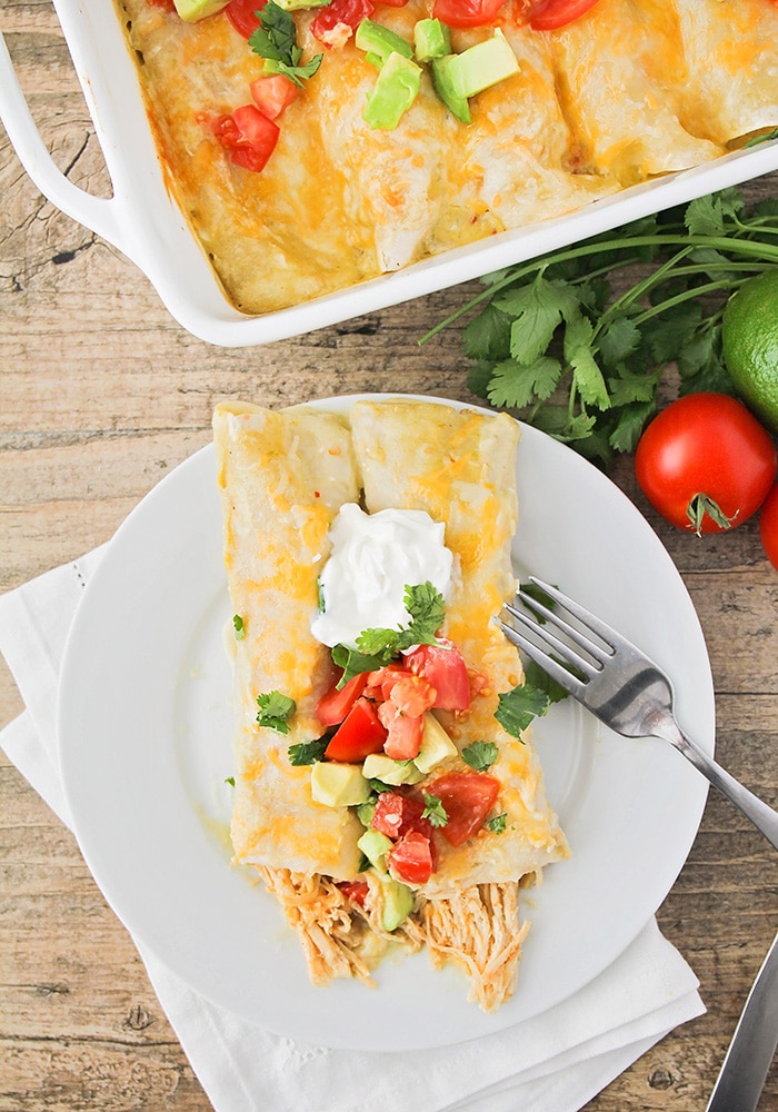 a tray of enchiladas topped with sour cream and green sauce