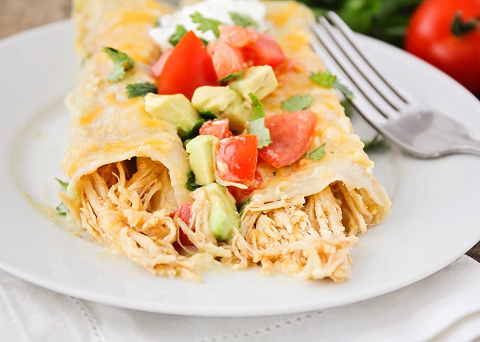 honey lime chicken enchiladas topped with tomatoes and avocado