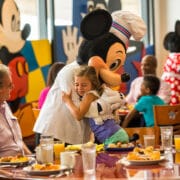 little girl hugging mickey in a restaurant
