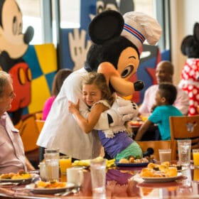 little girl hugging mickey in a restaurant