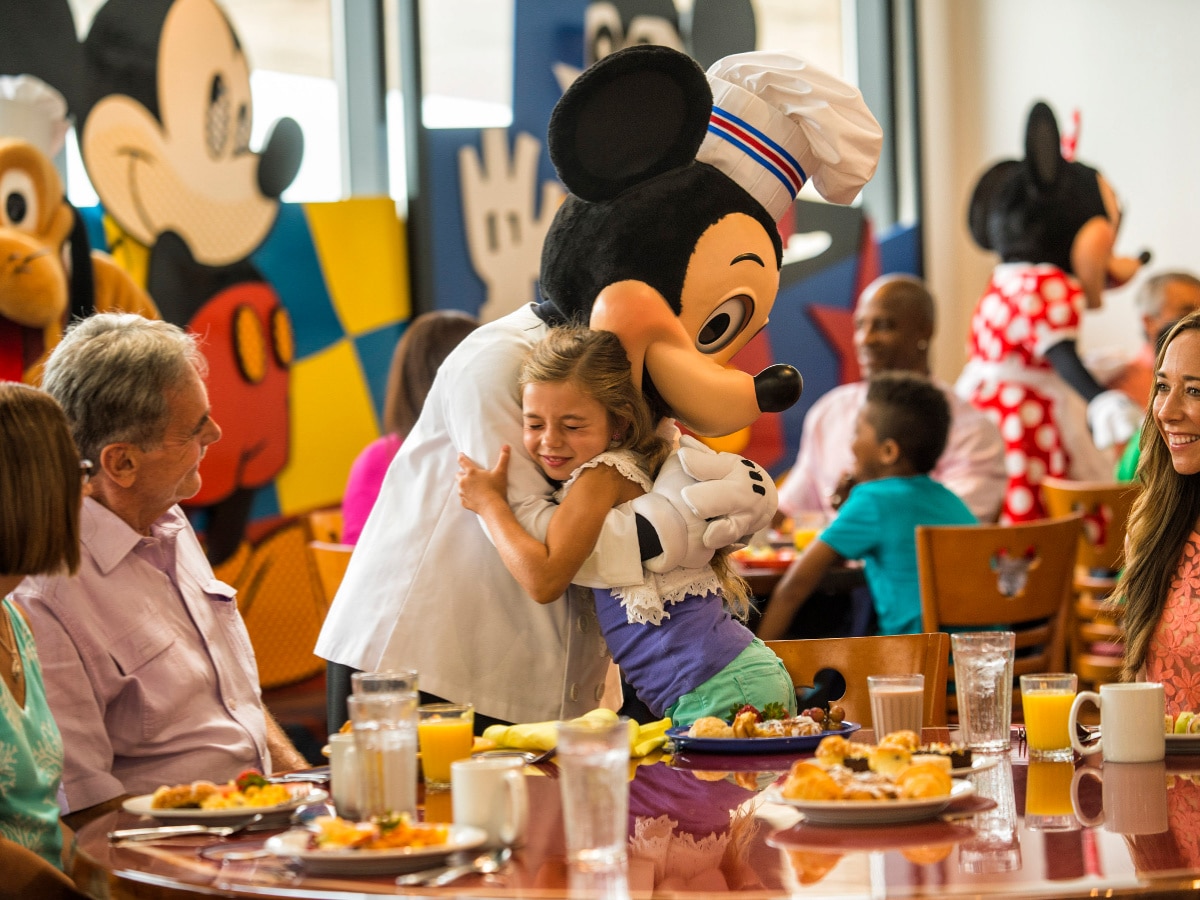 little girl hugging mickey in a restaurant