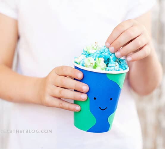 child holding a cup that looks like the earth filled with blue and green popcorn