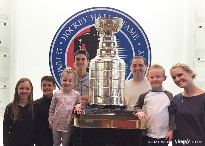 a family of seven standing around the Stanley Cup at the Hockey Hall of Fame in Toronto Canada