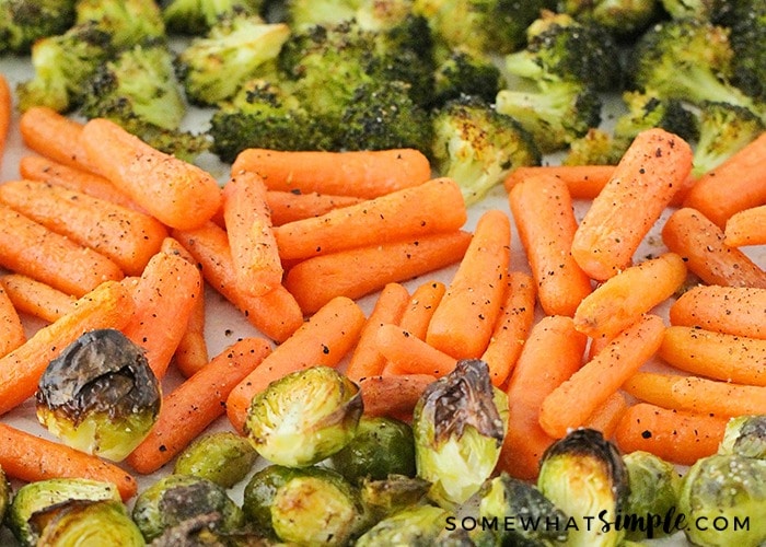 a tray of oven roasted vegetables that includes broccoli, carrots and Brussels sprouts