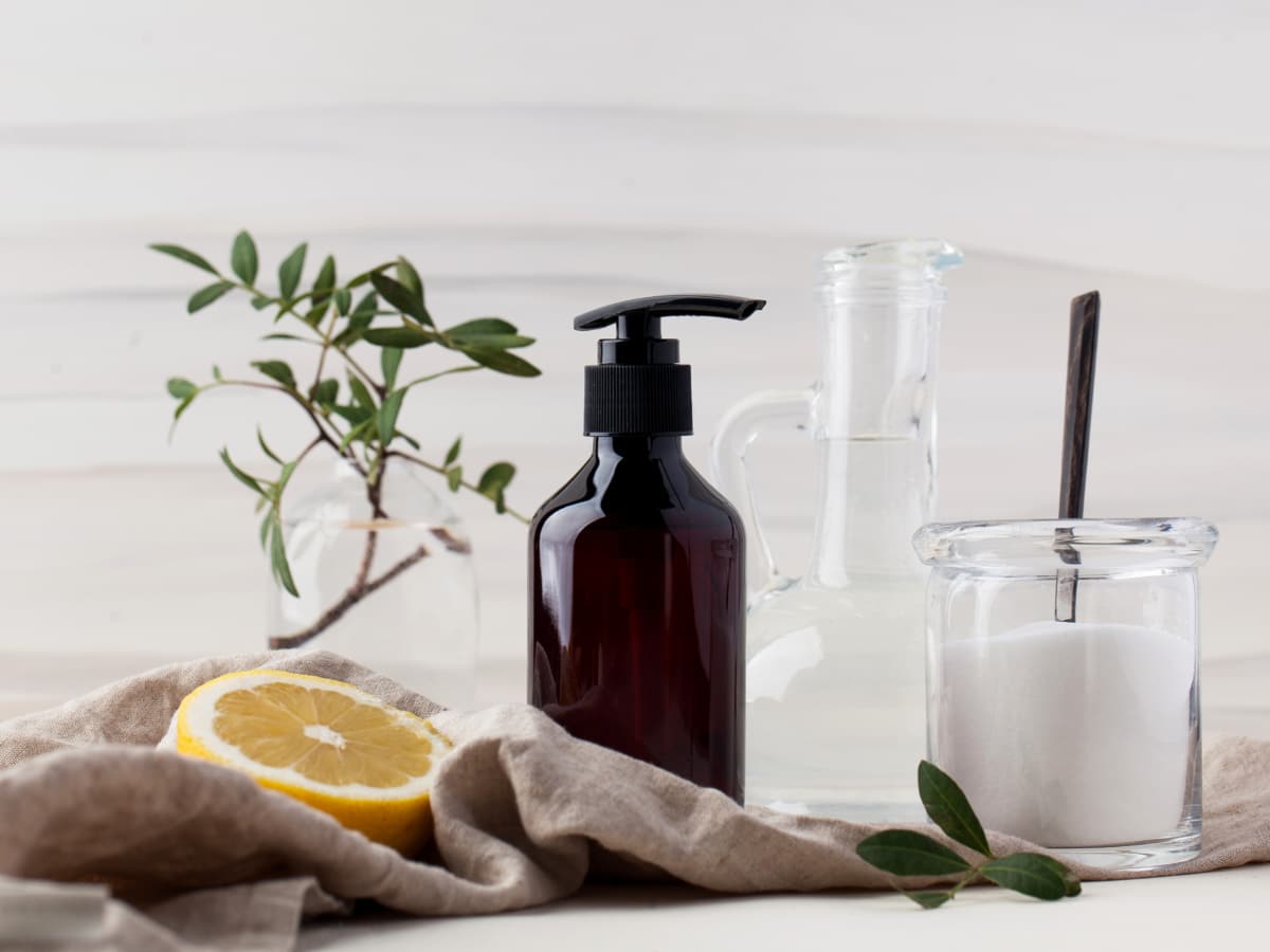 cleaning supplies next to a small plant and sliced lemon