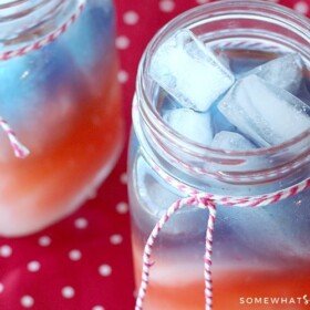 looking down on two Mason jar glasses filled with a layered red white and blue 4th of july drink