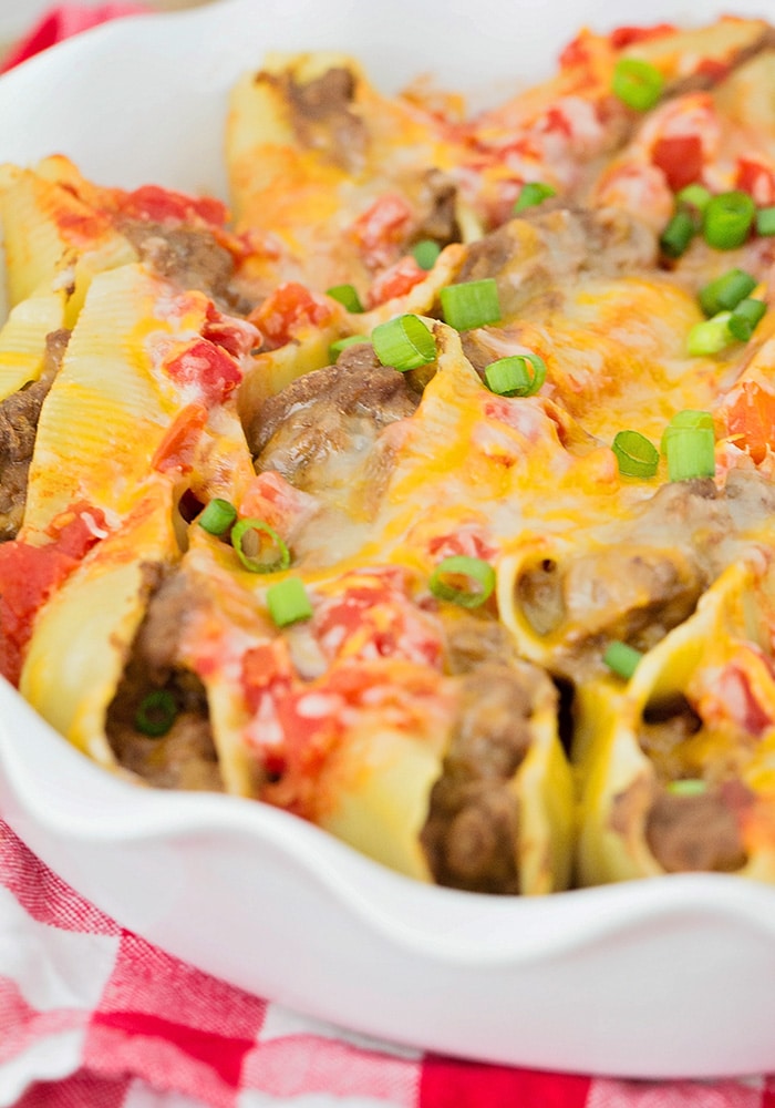 a close up of stuffed pasta shells filled with ground beef and topped with melted cheese and green onions