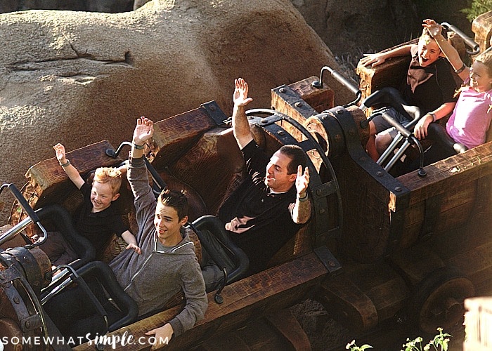  An adult man with four children riding the Seven Dwarfs Mine Train at Disney's Magic Kingdom is one of the Best Magic Kingdom Rides and Attractions