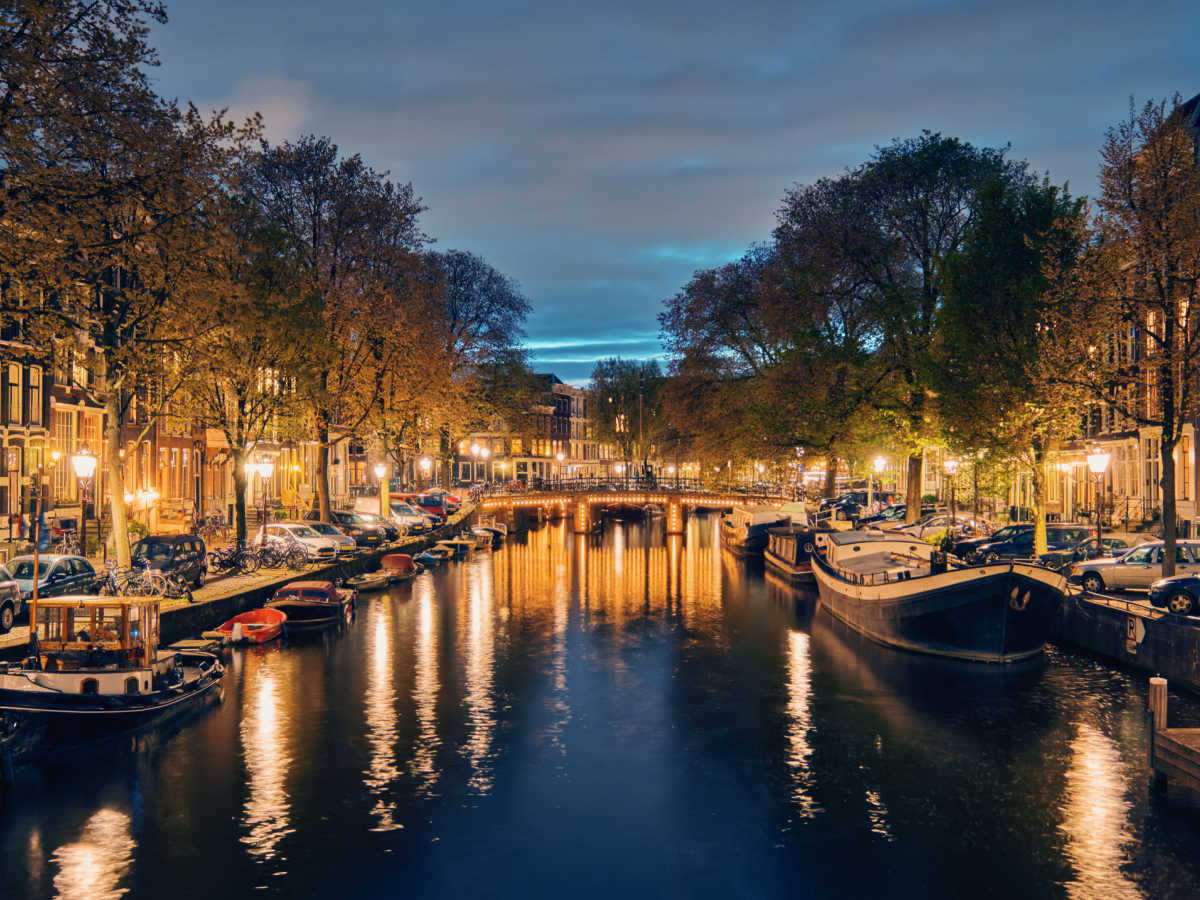 nighttime in amsterdam with glowing city lights by the canal