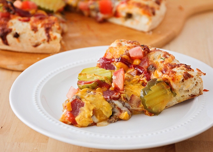 a slice of bacon cheeseburger pizza on a white plate