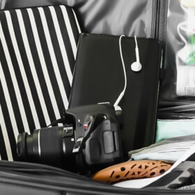 packing tips a camera, a tablet and a laptop case sitting on top of an open suitcase