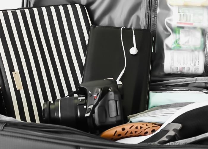 a camera, a tablet and a laptop case sitting on top of an open suitcase