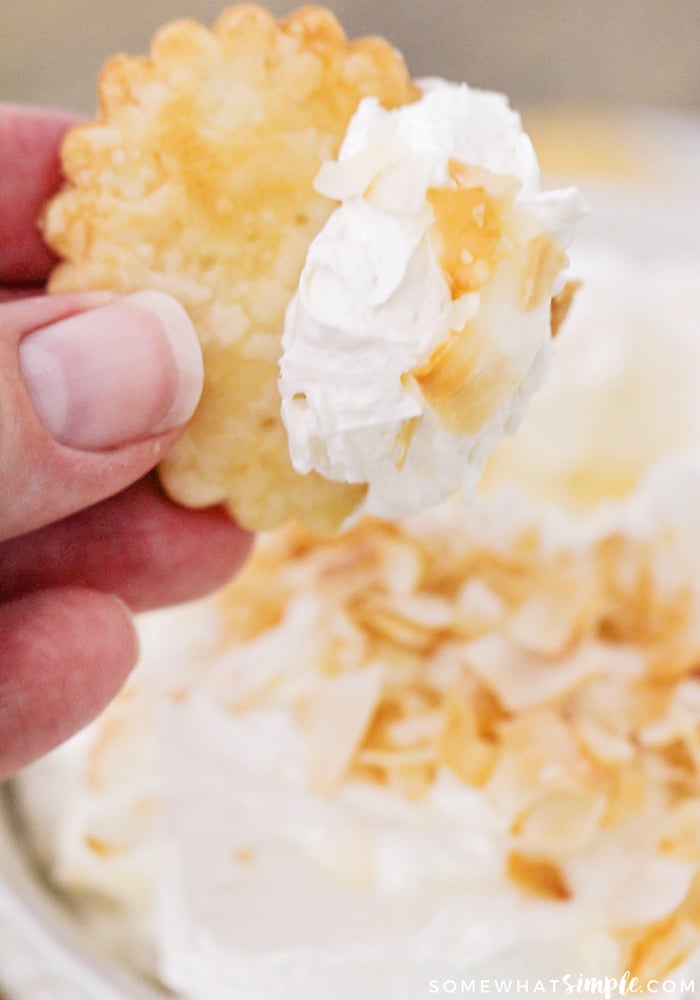 a cookie dipped in a coconut dessert dip