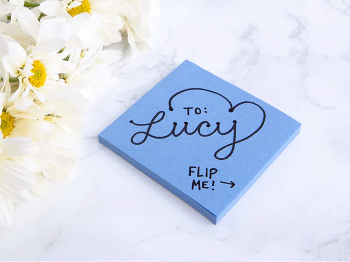 blue sticky notes made into a flip book next to flowers on a white counter