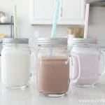 Chocolate, strawberry and vanilla Slim Fast shakes in mason jar glasses on a counter and each have a pastel colored straw