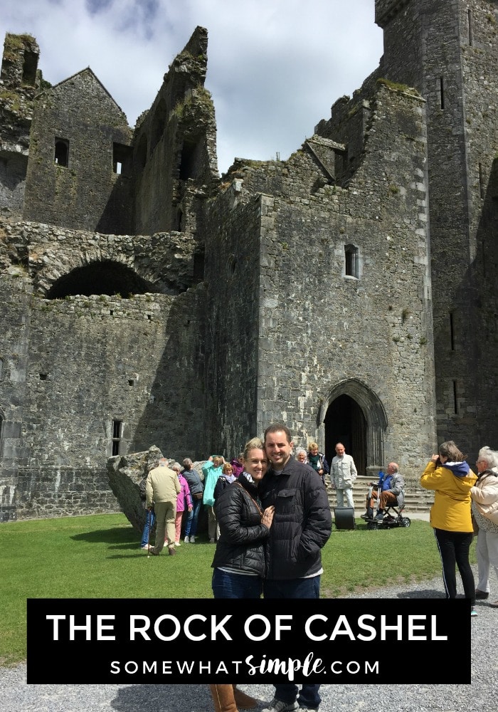 an attractive couple standing in from of the rock of cashel chapel in southern ireland