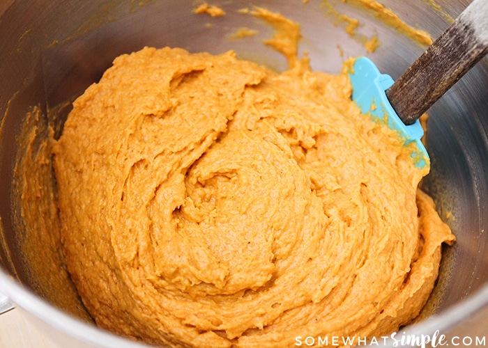 a metal bowl filled with orange cookie batter
