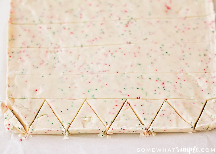 Shortbread Christmas Cookie dough on a counter with triangle shapes cut into the dough.