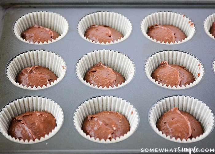 chocolate batter in cupcake wrappers in a grey cupcake baking sheet made from this Homemade Hostess Cupcakes recipe