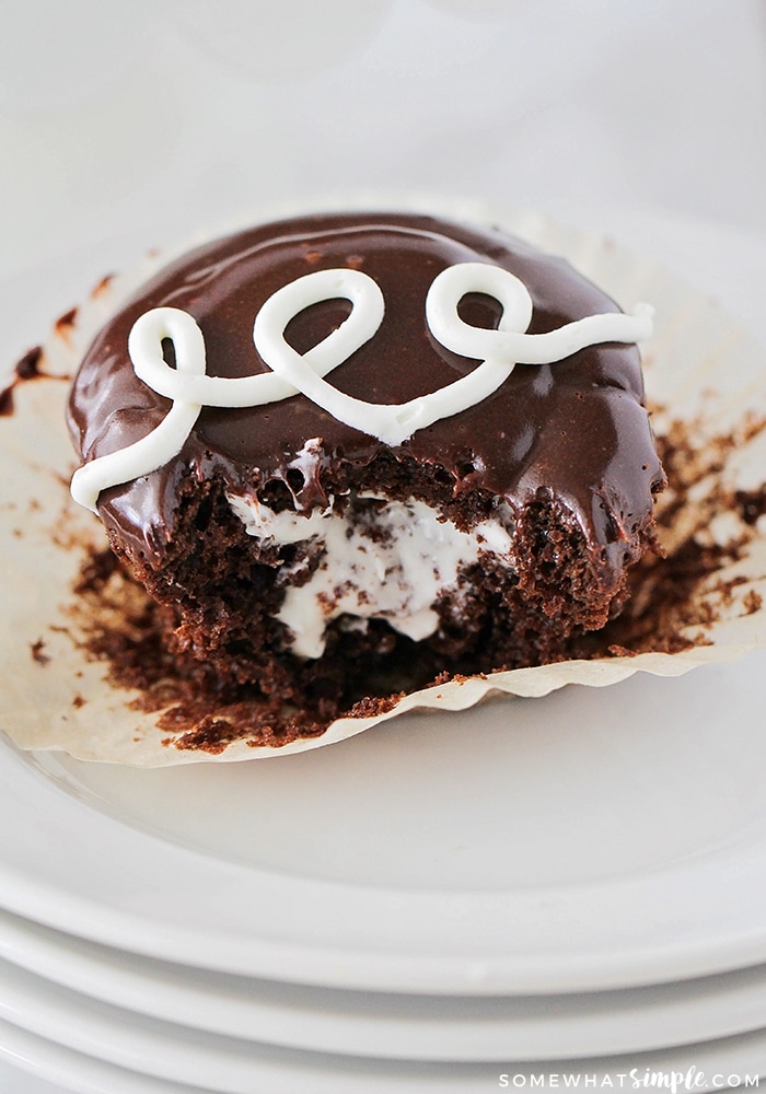 close up picture of a Homemade Hostess Cupcake that has a bite taken out and the cream filling is showing inside the chocolate cupcake