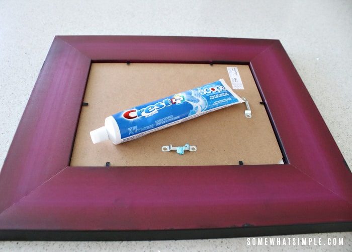 a tube of toothpaste laying on the back of a picture frame