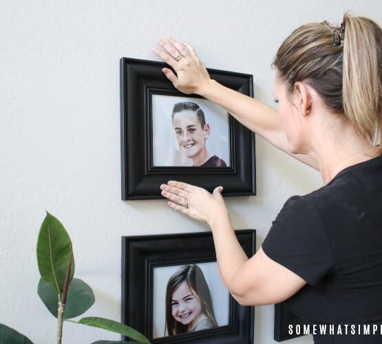 a beautiful woman hanging a picture on a wall