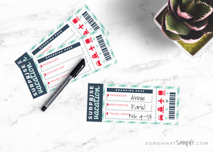 surprise vacation printable tickets on a counter next to a plant and black pen