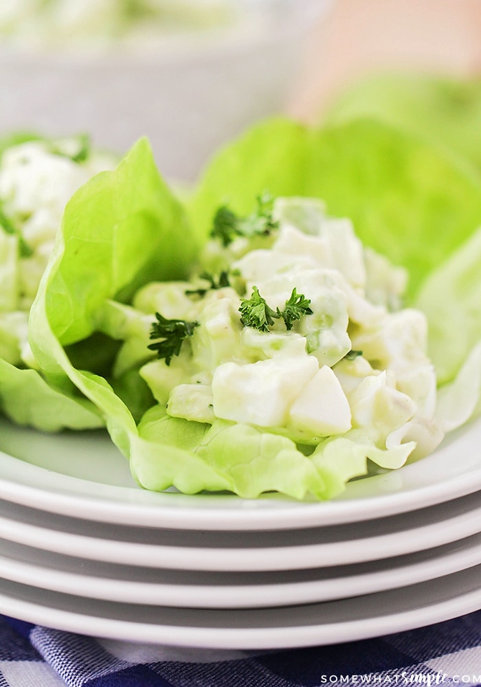 a close up of a large leaf of lettuce with a scoop of egg salad made with avocado on top