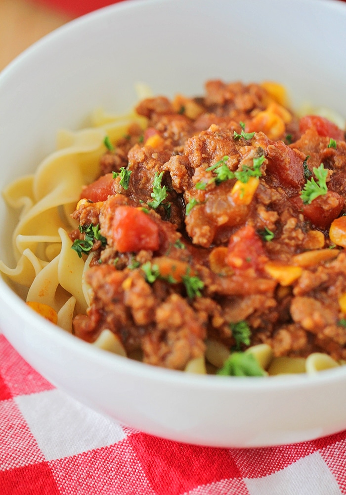 a close up of a white bowl filled with american goulash which is made up of pasta and topped with goulash 