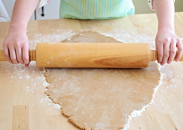 kids hands rolling out gingerbread dough