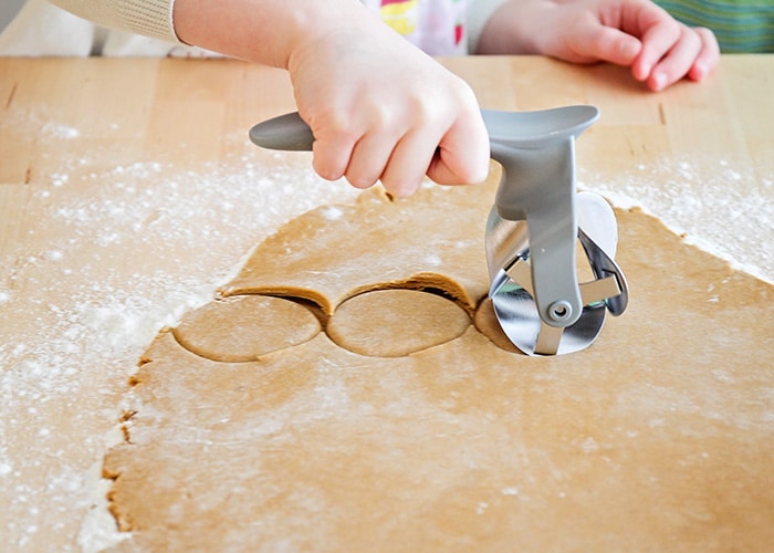 a rolling cookie cutter cutting out dough