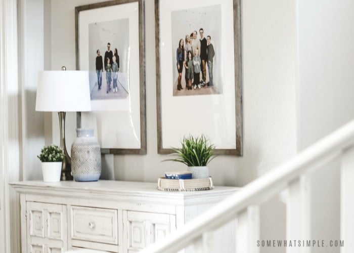 a white cabinet with two family pictures on the wall above it.