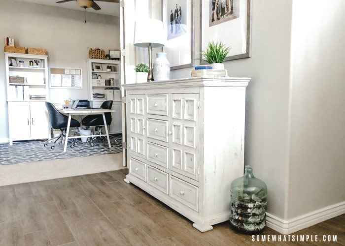 a white cabinet against the wall in the entry way of a home