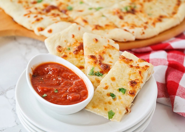 Cheesy Breadsticks on a white plate with a side of maranara sauce is a simple super bowl food to make