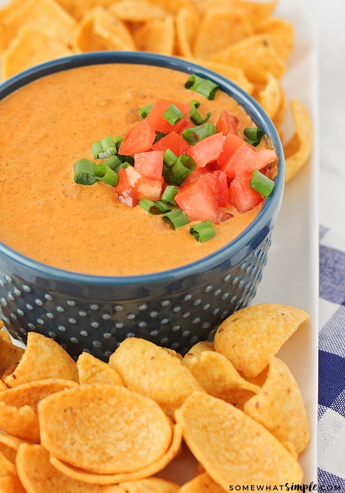 a bowl of Best Chili Cream Cheese Dip made using this easy recipe on a serving tray with Frito scoop chips