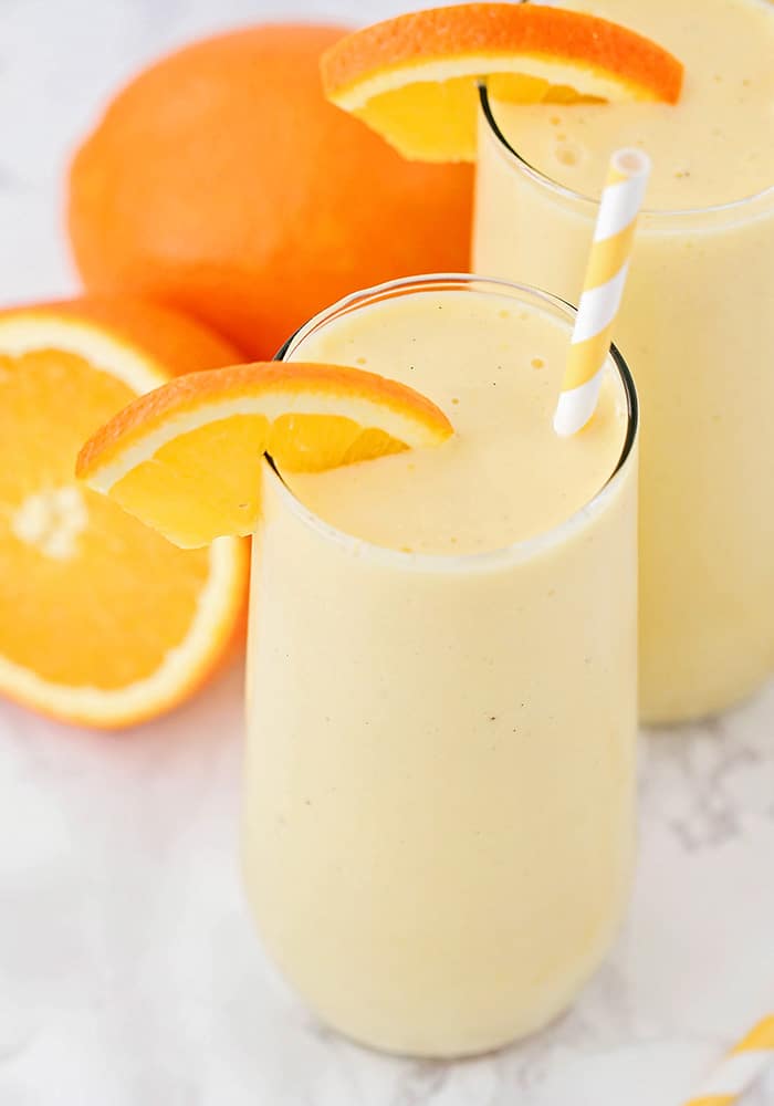 two glasses of frozen orange smoothies on a white counter