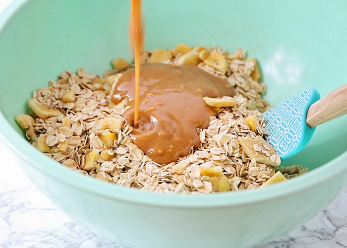 adding melted peanut butter to a bowl of oatmeal