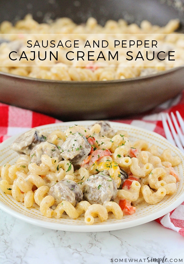 bowl of sausage and pepper Cajun cream sauce pasta with a skillet of the pasta in the background