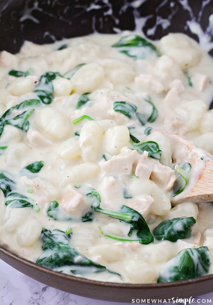 a pot of chicken gnocchi with fresh spinach