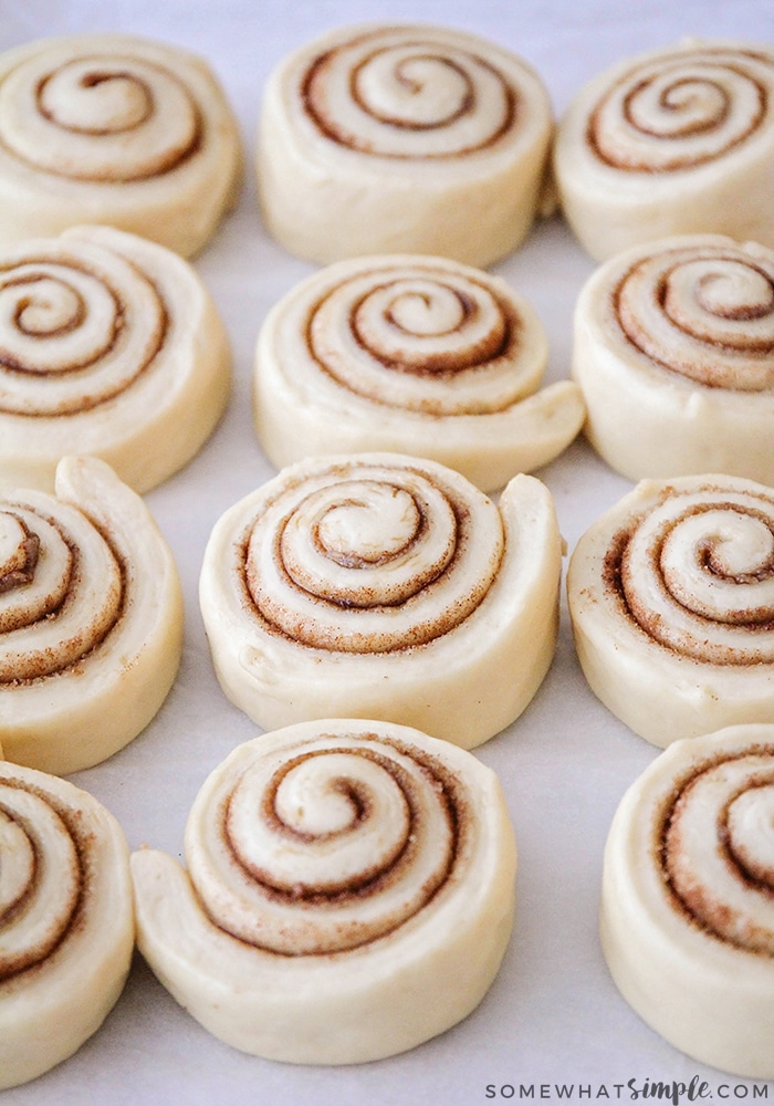 raw cinnamon rolls that have been cut and laid out on a baking sheet that are ready to go in the oven