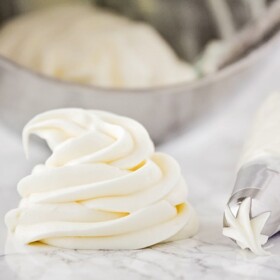 a swirl of homemade cream cheese frosting on a counter with a piping bag laying next to it