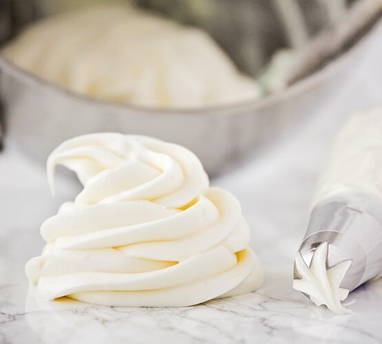 a swirl of homemade cream cheese frosting on a counter with a piping bag laying next to it
