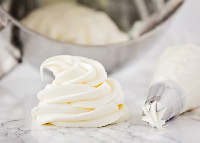 a swirl of homemade cream cheese frosting on a counter with a piping bag laying next to it