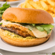 plated chicken sandwich on a white plate with french fries in the background