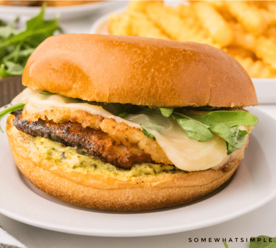 plated chicken sandwich on a white plate with french fries in the background