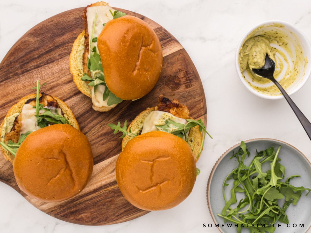 over head shot of 3 chicken sandwiches on a brown cutting board