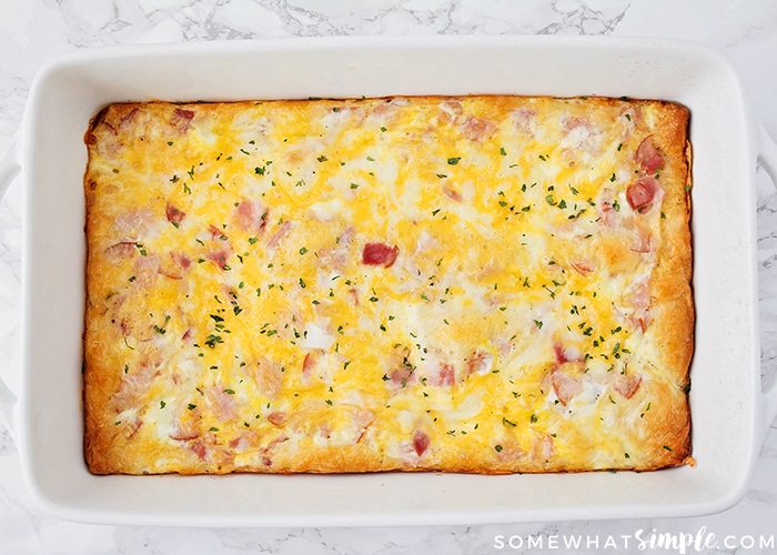 looking down on a white casserole pan filled with a breakfast egg casserole that has been baked in the oven and is a golden brown on top