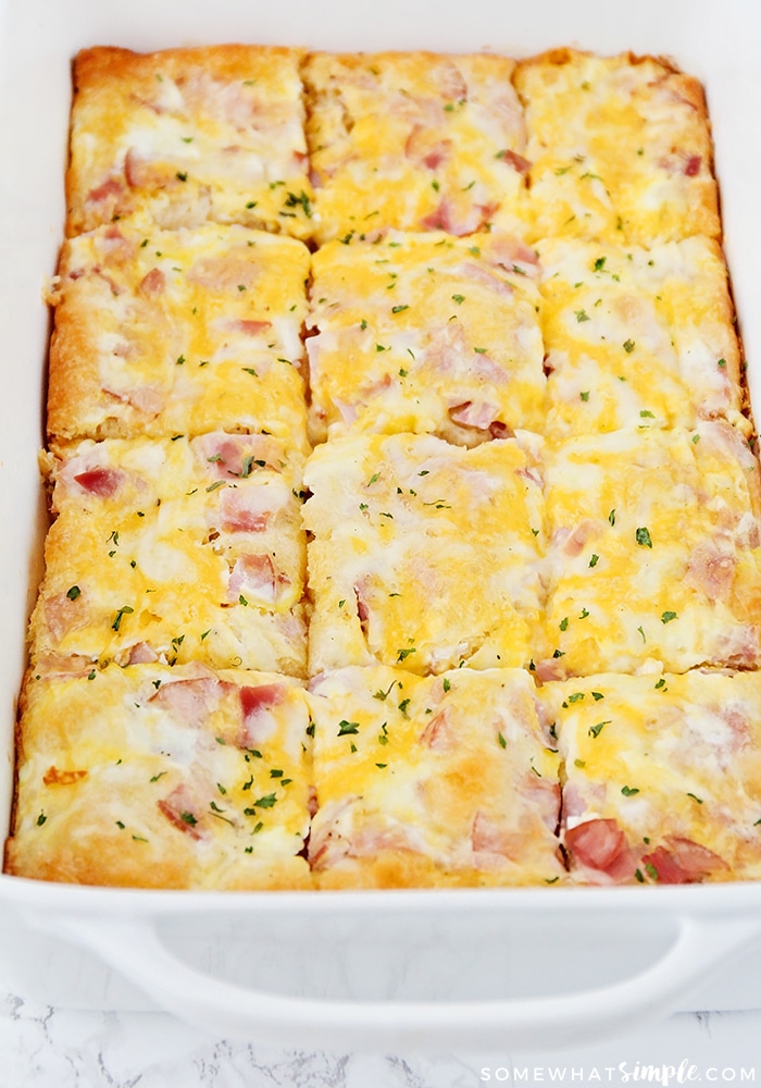 a casserole pan filled with a cooked breakfast casserole that was made with this easy recipe using cheese, eggs, ham and croissant dough and has been cut into twelfths.