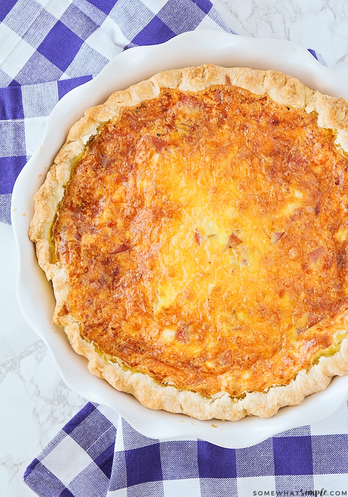 looking down on a full round baking tray filled with a golden brown ham and cheese breakfast quiche