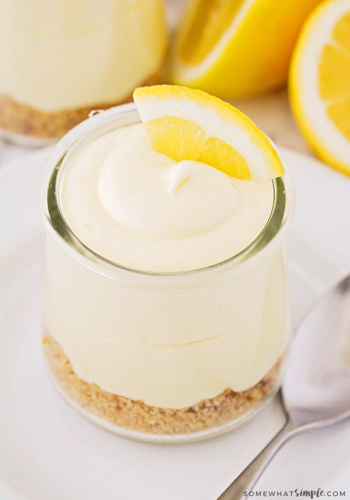 looking down on a cup filled with lemon cheese cake mousse on a graham cracker crust bed with a lemon wedge on on top